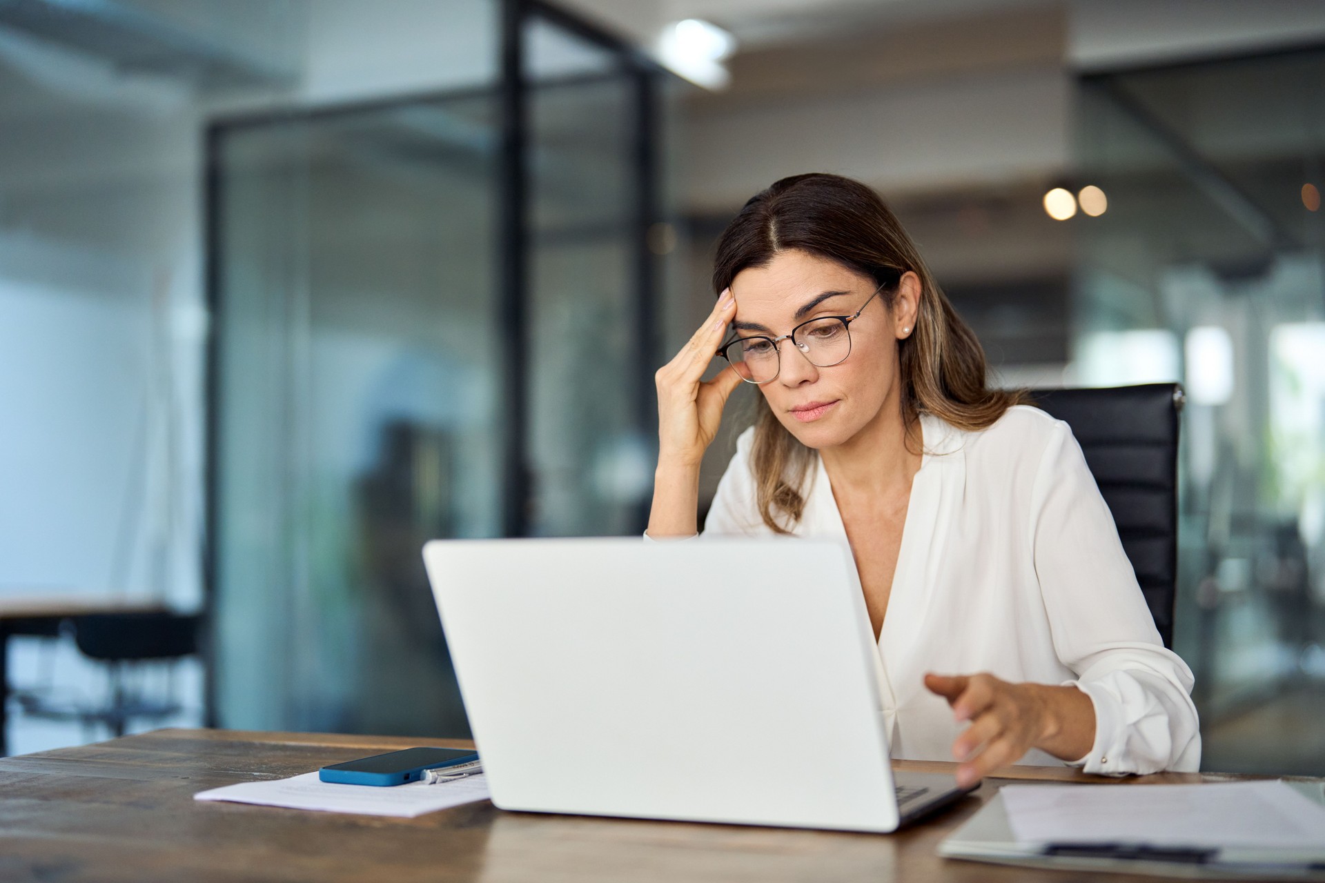 Worried fatigued mature business woman wearing glasses having headache at work.