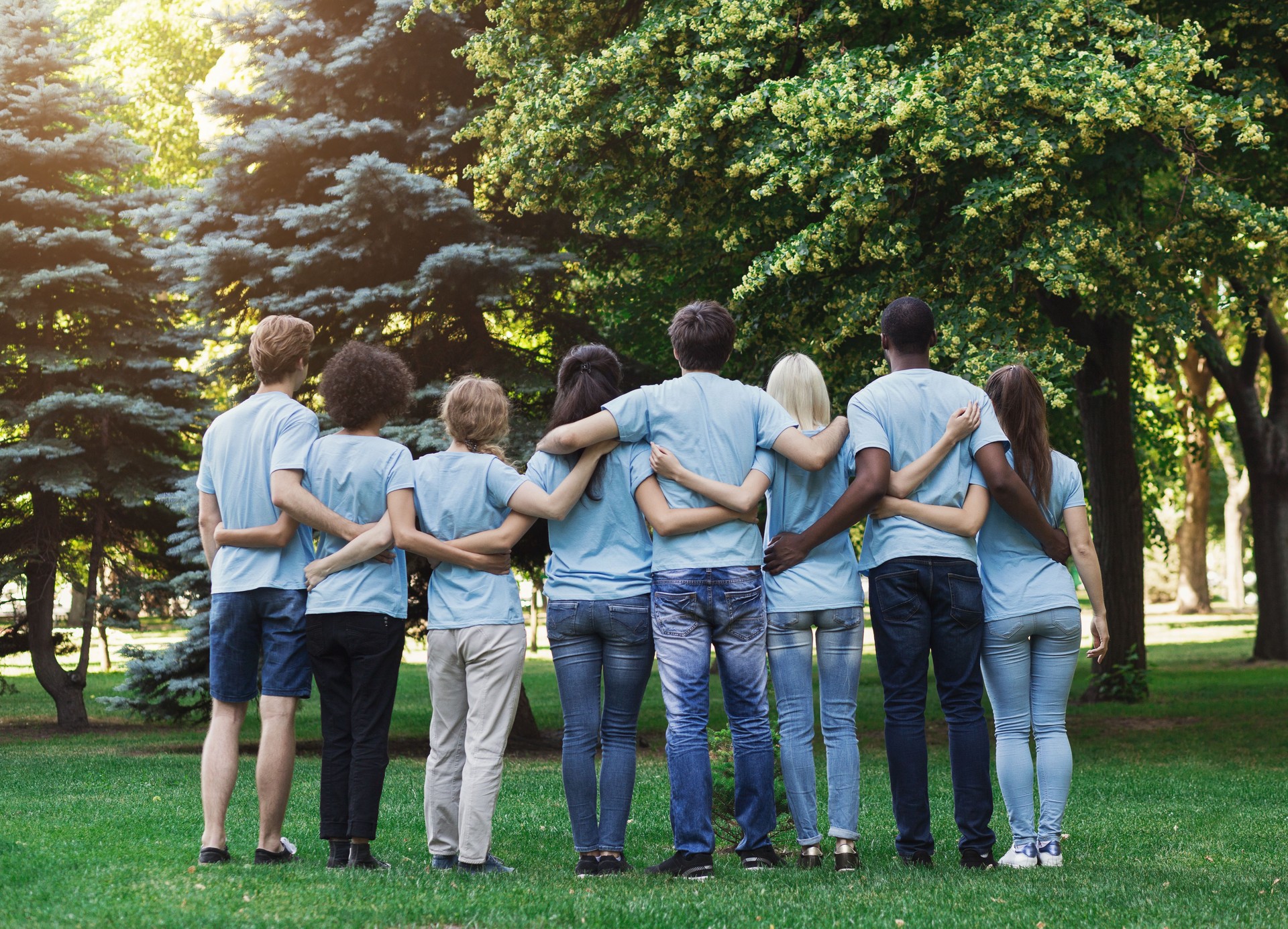 Group of happy volunteers embracing in park